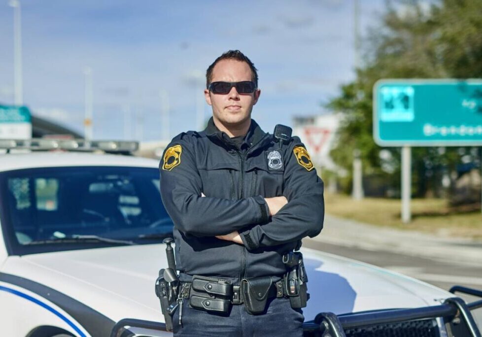 Police officer standing in front of patrol car.